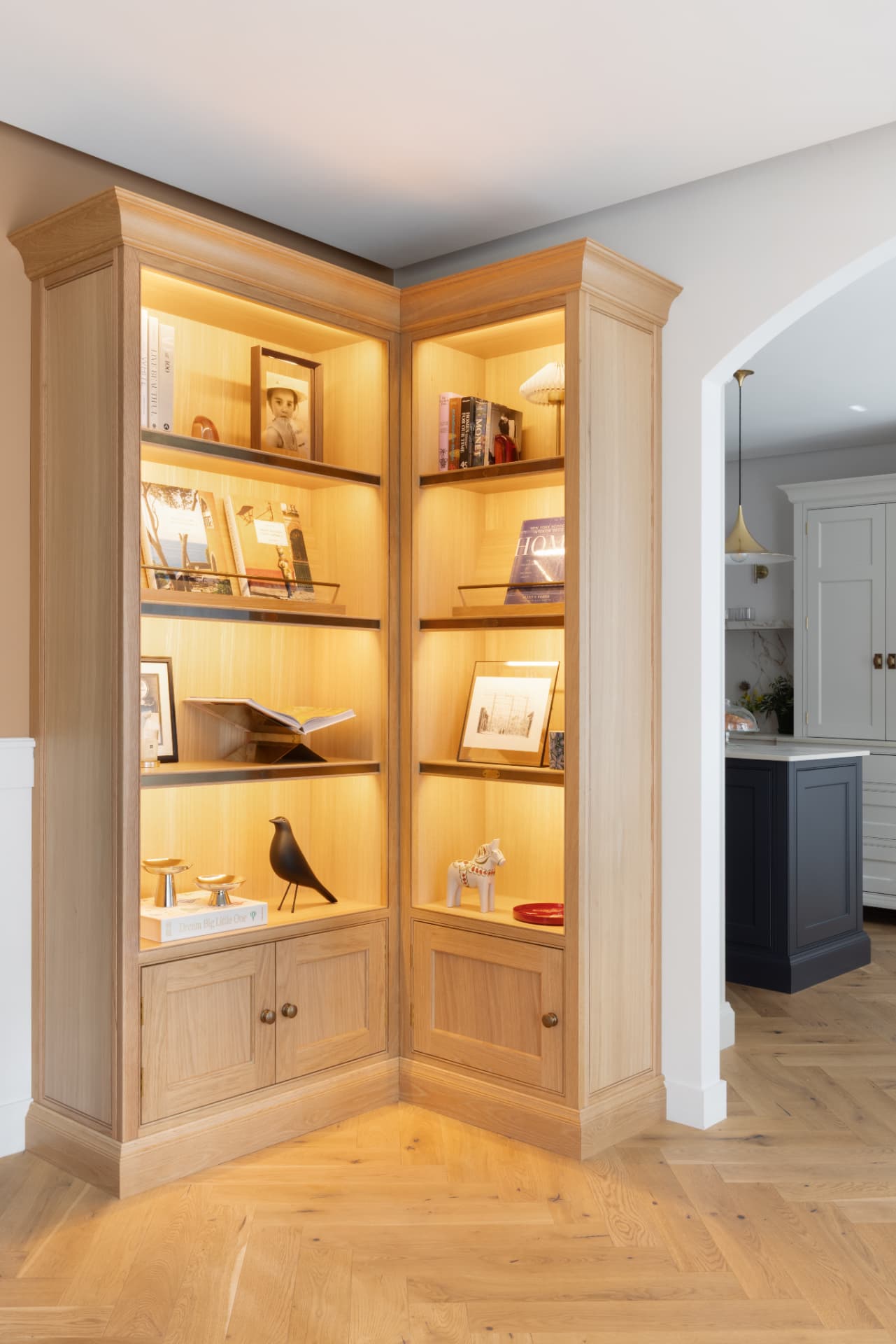Lake Geneva House — illuminated oak corner library with brass shelf rails and displayed books