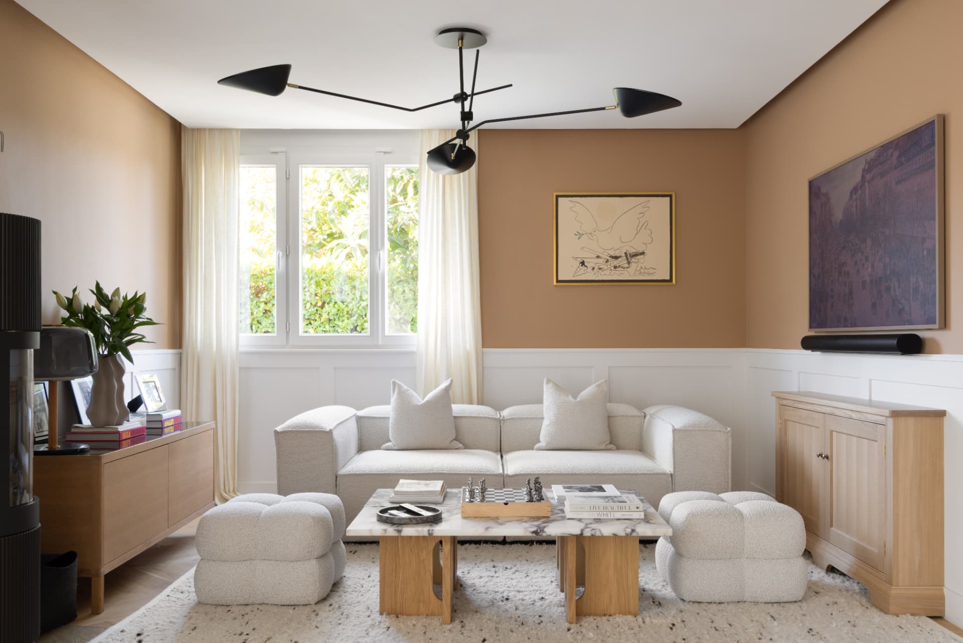 Sitting room with warm tan walls, bouclé sofa, oak sideboard and a sculptural black ceiling light